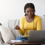 This is an image of a woman studying in her home. She has a laptop infront of her. 